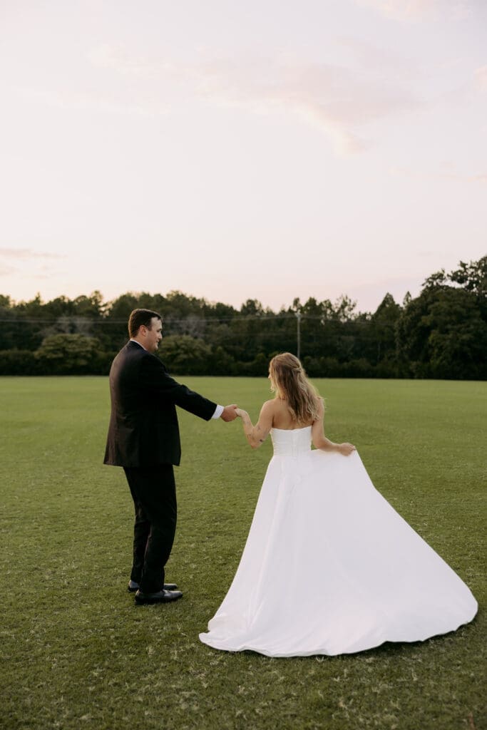 golden hour bride and groom portraits at twin fields estate, bride and groom twirling in the field at venue