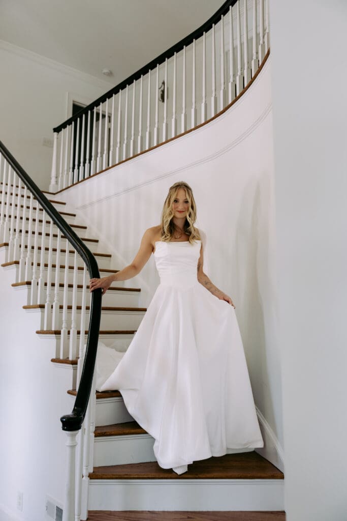 bride walking downstair case at twin fields estate venue in her wedding dress